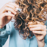 Young woman in blue shirt holding her curly hair tips 732x549 thumbnail